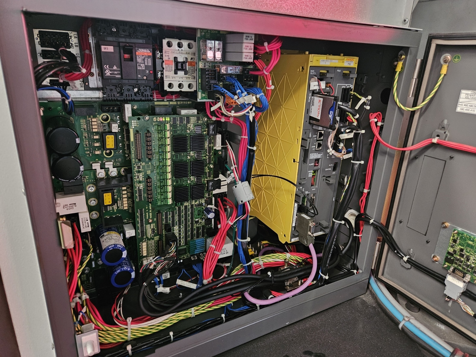 Interior of an industrial control panel with circuit boards and colorful wiring harnesses.